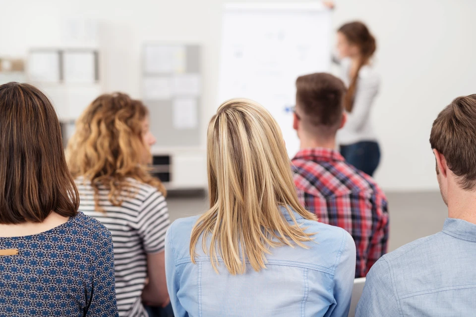 Le public lève la main tandis que le chef d'entreprise parle en formation au bureau