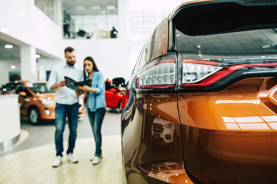 Concession automobile avec couple consultant une brochure dans un showroom moderne