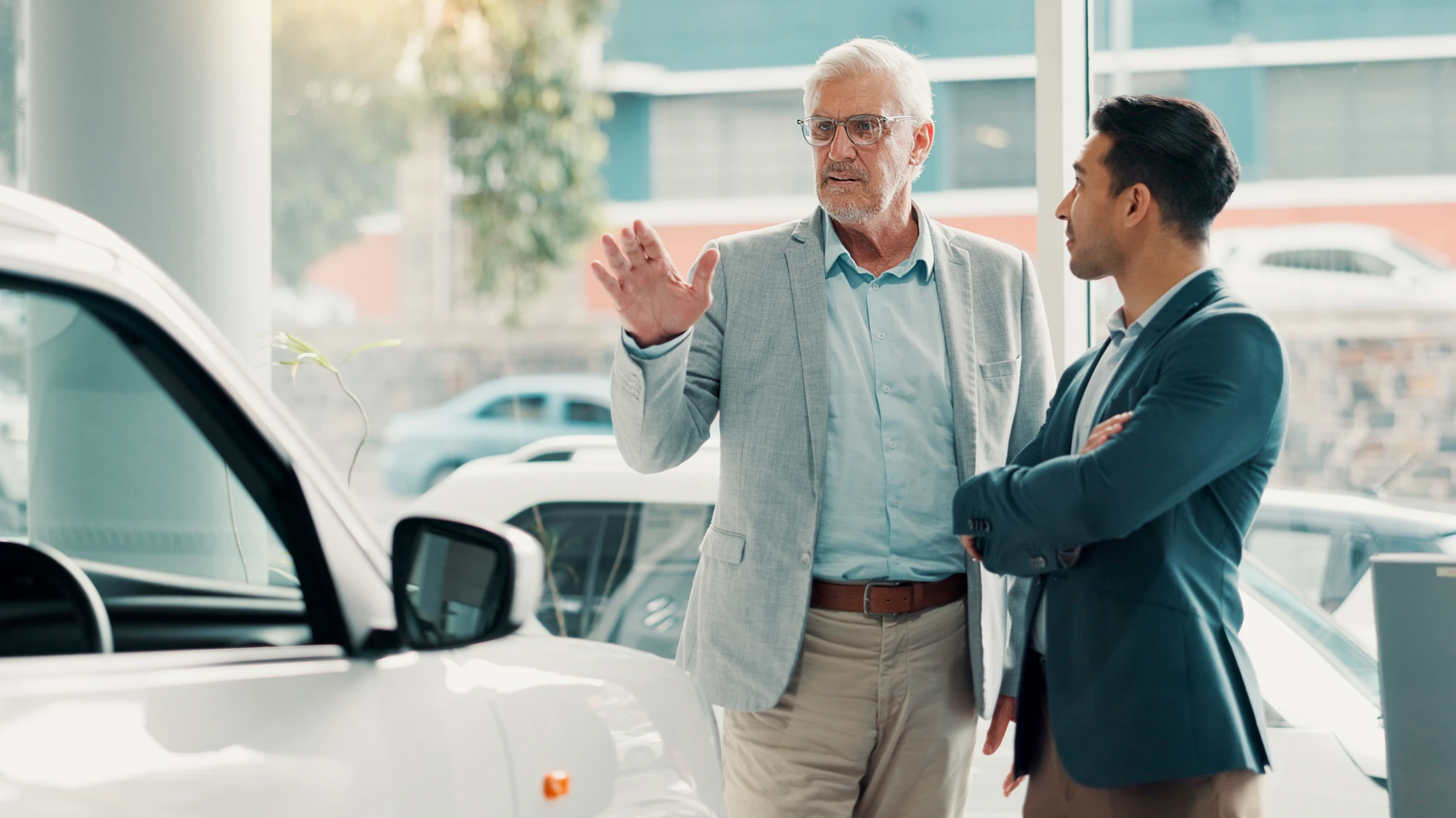 Showroom automobile moderne avec trois personnes discutant autour d'un véhicule noir