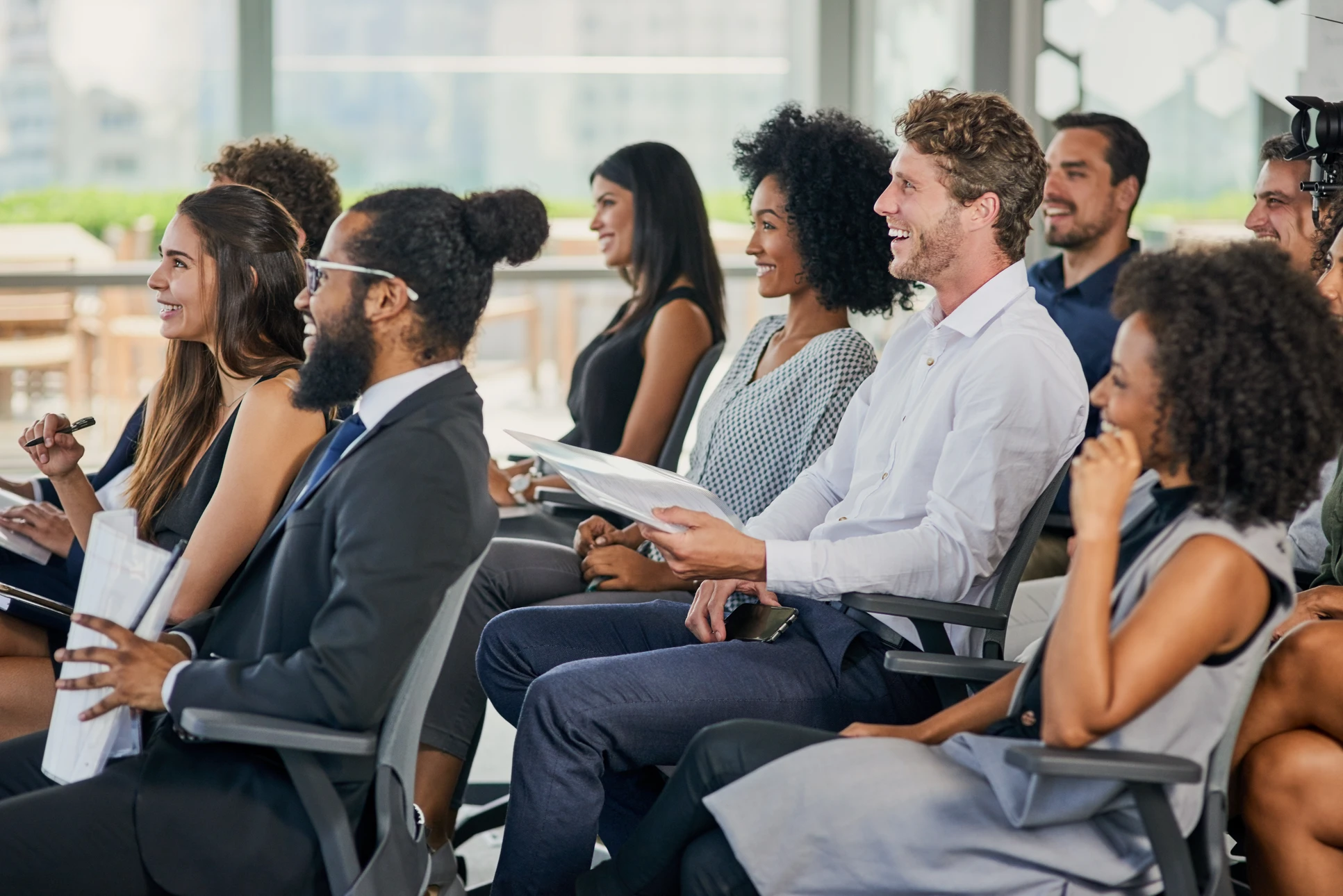 Salle de formation moderne avec groupe de participants assis face à un formateur debout près d'un tableau blanc